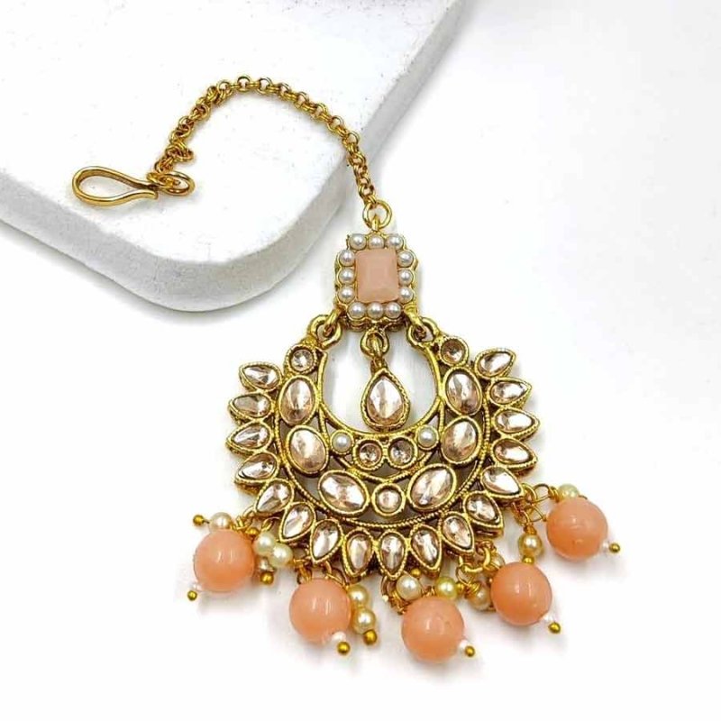 Peach colour wonderful classy traditional mang tikka form kayaa fashion for stylish women like you. It is wonderfully styled with stone and made form metal. This classy mang tikka has pearls beads droplets for stylish look. Buy now!