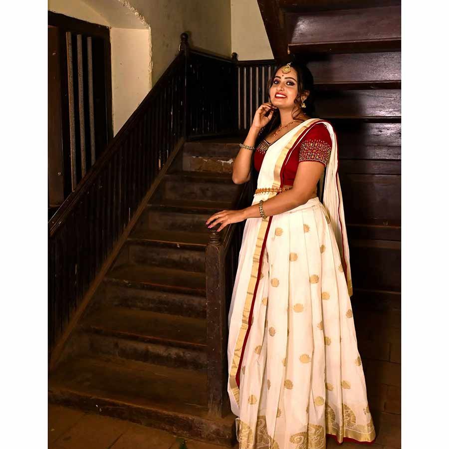 Setting the bridal trousseau trends high with our signature Kasavu Lehenga. A gorgeous ethnic attire, the maroon bodice is ornated with handcrafted zari and iconic motifs in decadent zardosi The voluminous skirt is crafted in Kerala Kasavu with Jacquard borders. Complementing the attire, is a pristine dupatta with zari buttas and contrast edging.